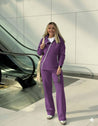 Woman in a purple outfit standing in front of an escalator.